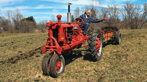 man in flannel riding a red tractor